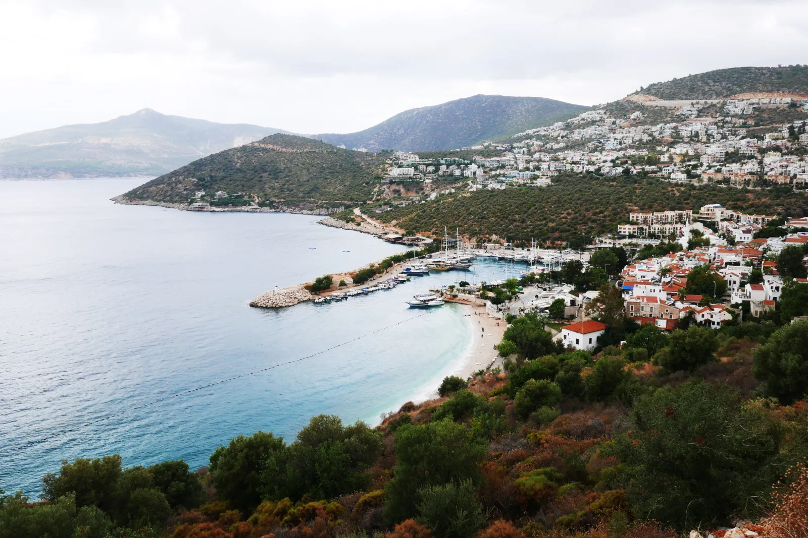 Kalkan koyu, yamaçtaki beyaz evler, küçük liman ve turkuaz deniz