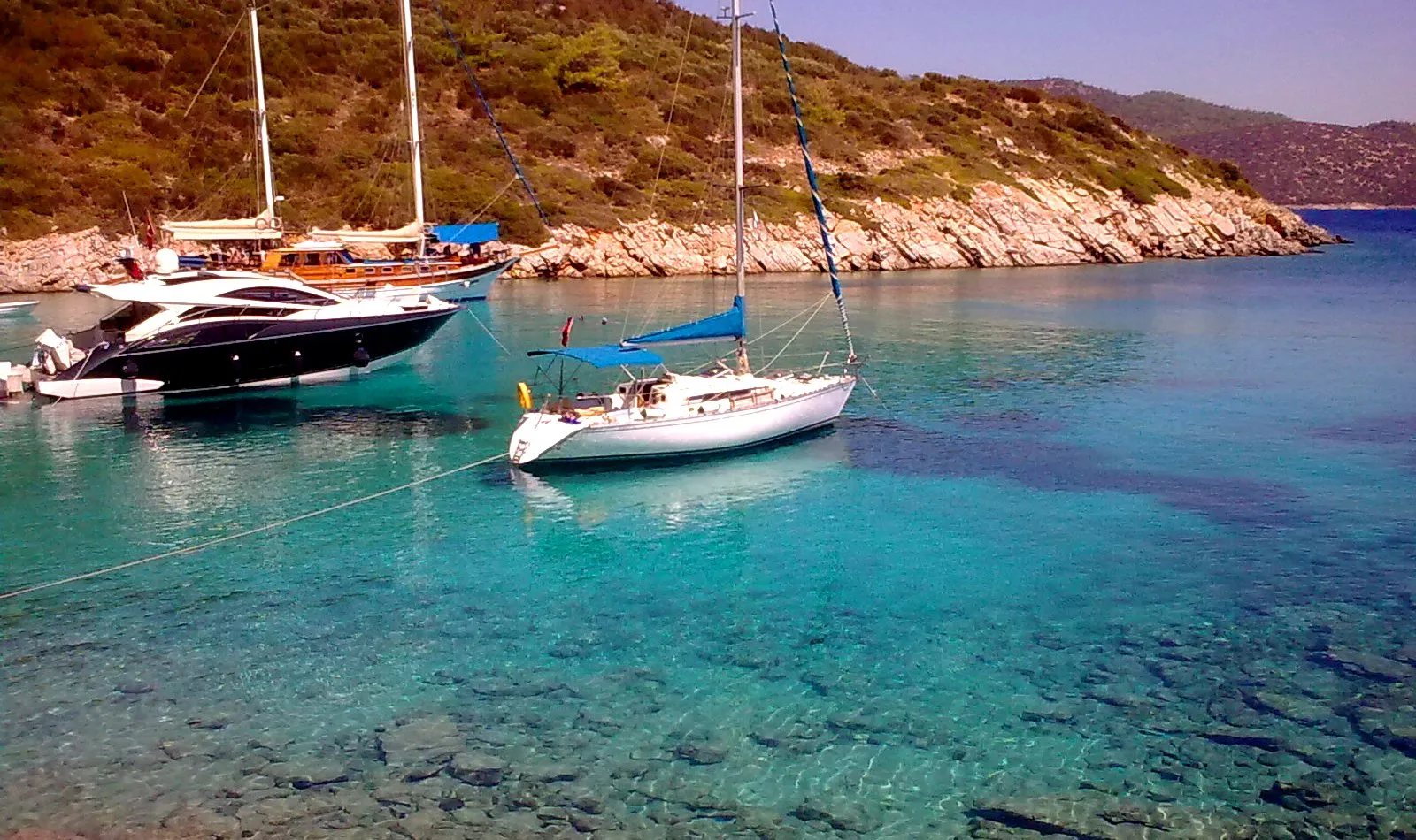 Bodrum açıklarında Orak Adası'nda turkuaz suda demirli yelkenli ve motoryat