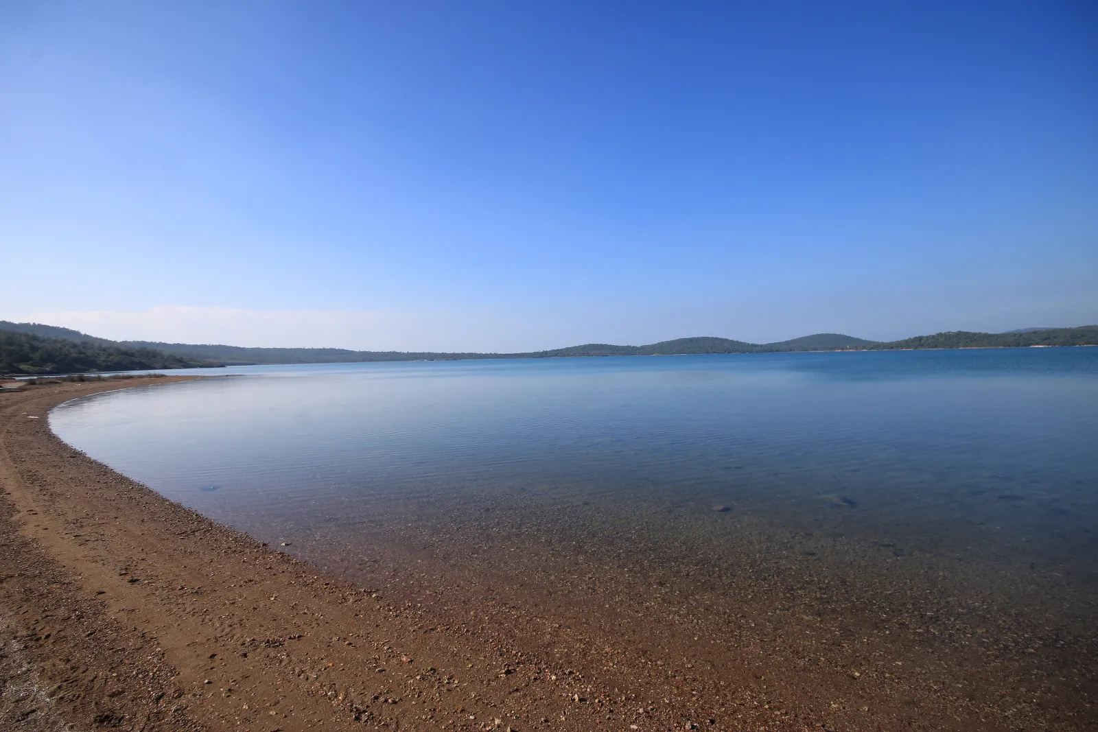 Ayvalık Adaları Tabiat Parkı'nda sakin bir koy, çakıllı kıyı ve durgun deniz