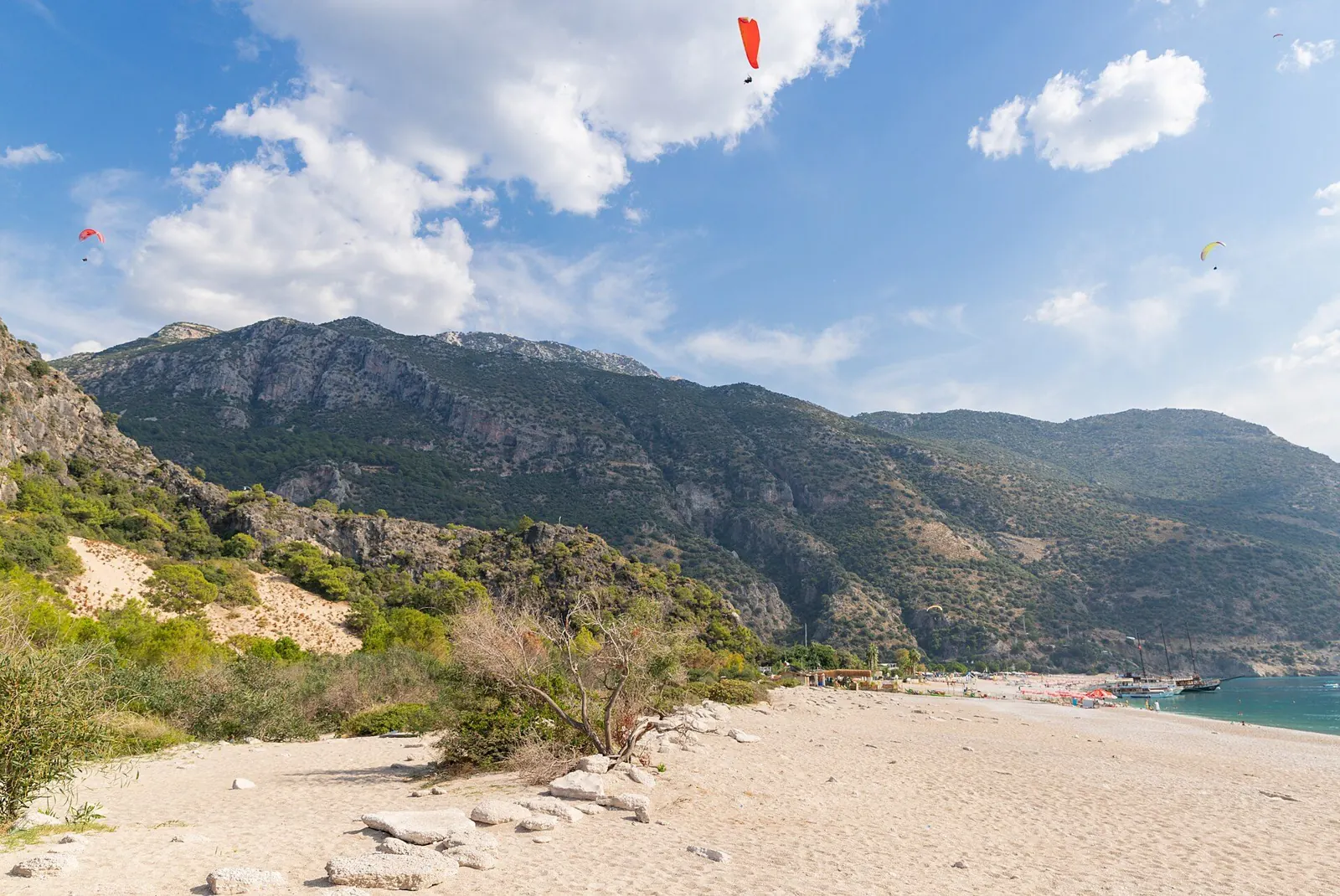 Ölüdeniz plajı üzerinde inişe geçen renkli yamaç paraşütleri