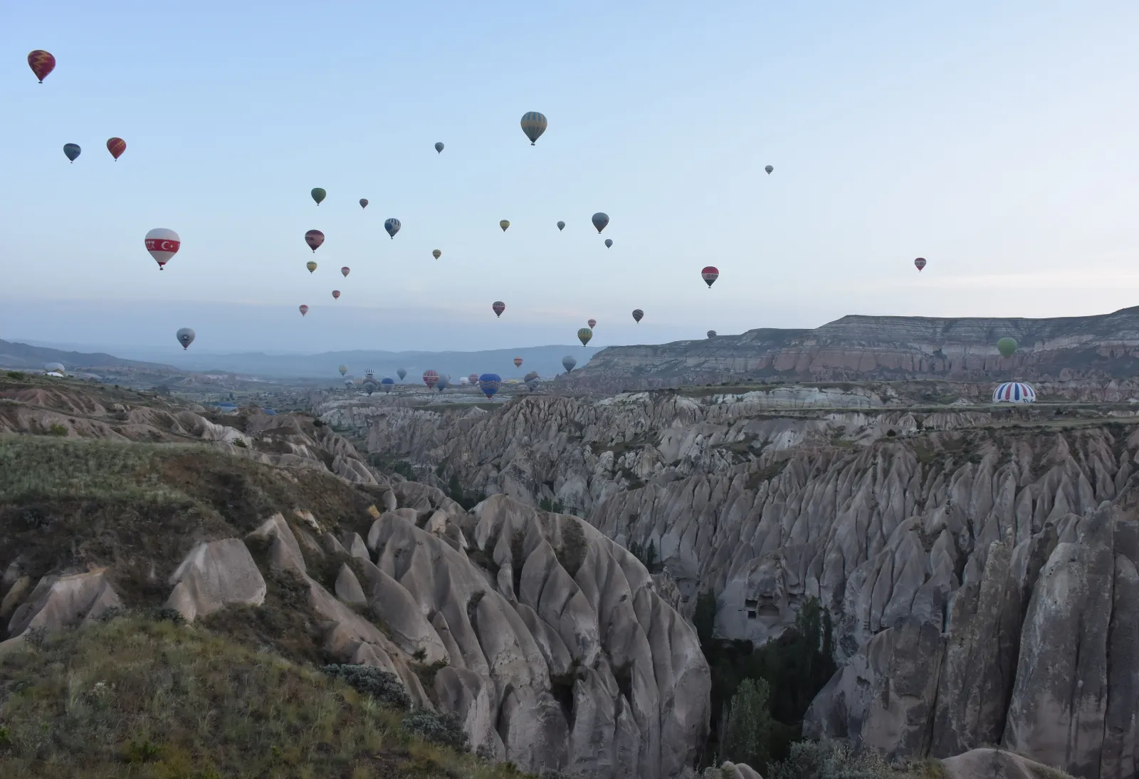 Şafakta Göreme yakınındaki vadilerin üzerinde yükselen çok sayıda sıcak hava balonu