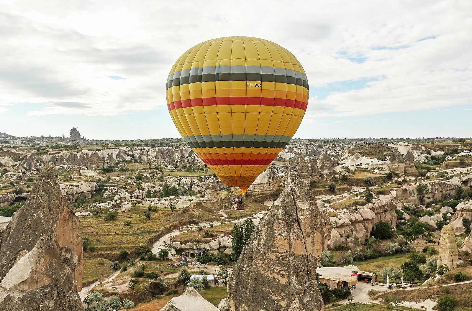 Kapadokya'da peribacaları üzerinde süzülen sarı kırmızı sıcak hava balonu
