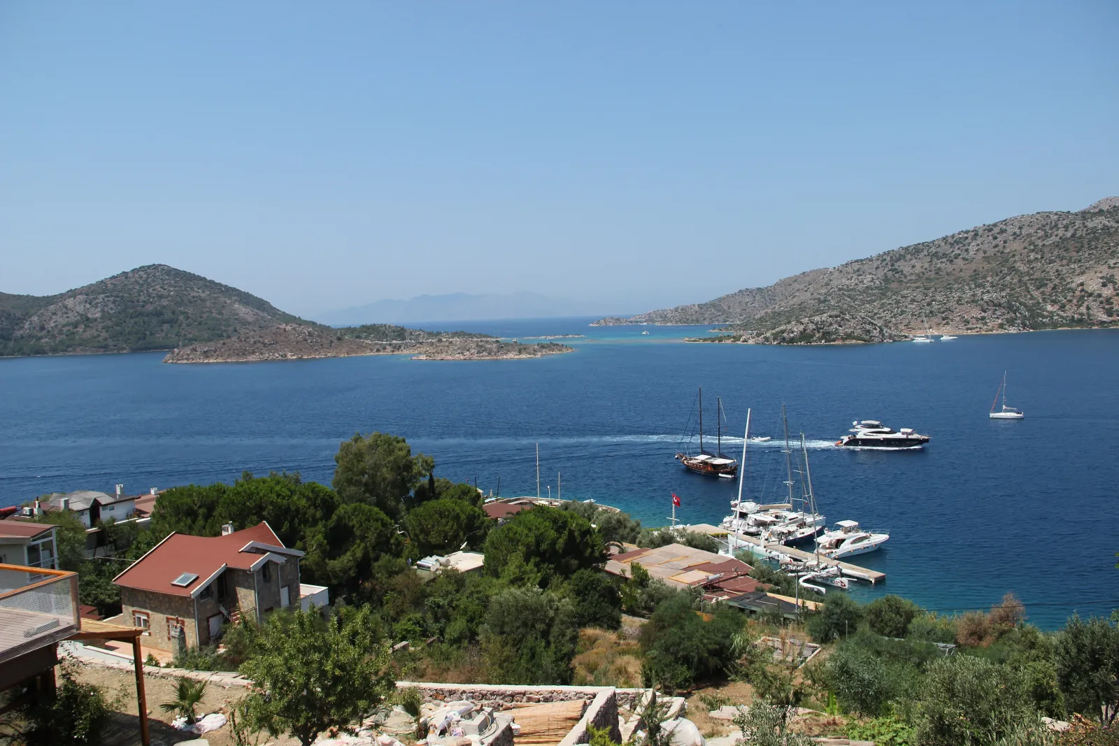 Bozburun'da taş evlerin önünde demirli yelkenliler ve karşıdaki adalar